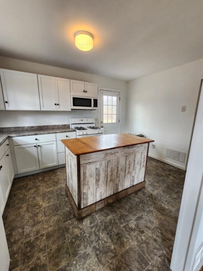 Kitchen featuring white cabinetry, white appliances, and butcher block counters