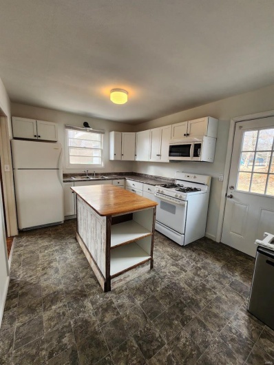 Kitchen featuring white appliances, butcher block counters, sink, and white cabinets