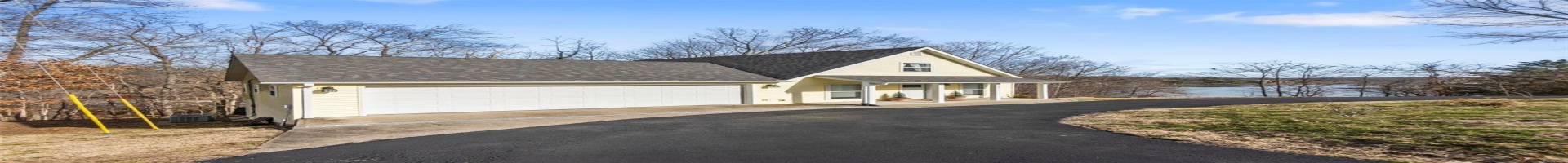 Residential For Sale View of front of the house with covered porch, a garage, and a water view