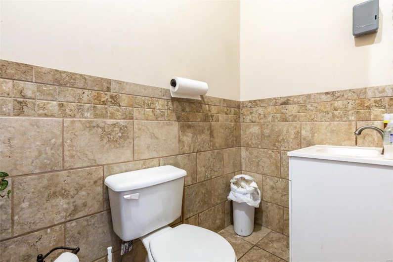 Bathroom featuring vanity, tile walls, and toilet