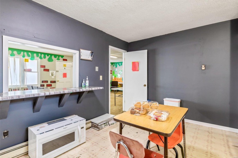 Kitchen featuring a breakfast bar, a textured ceiling, and baseboard heating