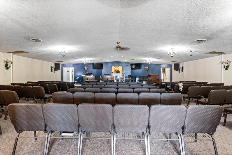 Cinema room with vaulted ceiling, light carpet, and a textured ceiling