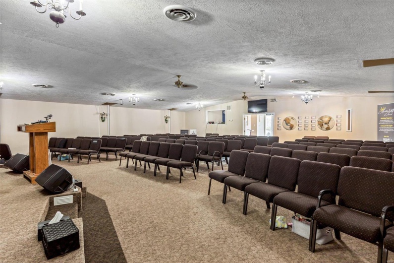 Carpeted home theater room with lofted ceiling and a textured ceiling