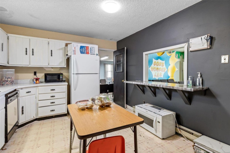 Kitchen featuring white cabinetry, white refrigerator, dishwashing machine, and a baseboard heating unit