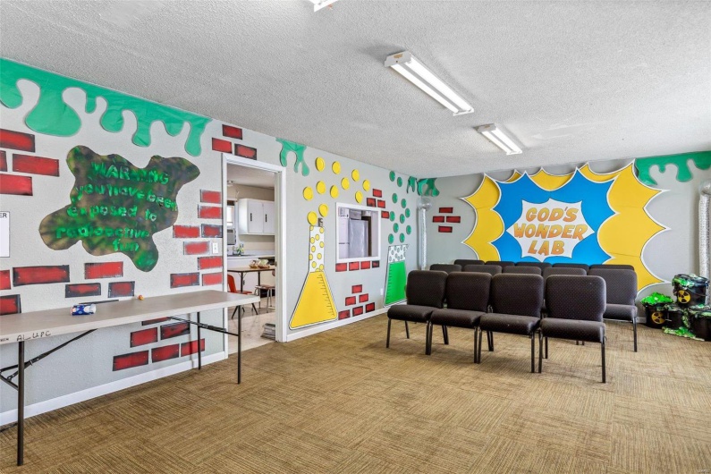 Recreation room featuring carpet and a textured ceiling