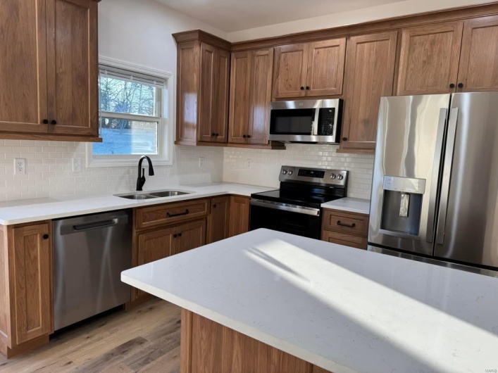 Kitchen with appliances with stainless steel finishes, sink, light hardwood / wood-style floors, and decorative backsplash