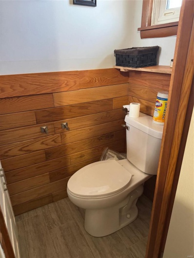 Bathroom featuring toilet, wood walls, and wood-type flooring