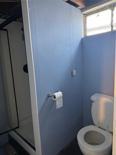 Bathroom featuring a shower with shower door and toilet
