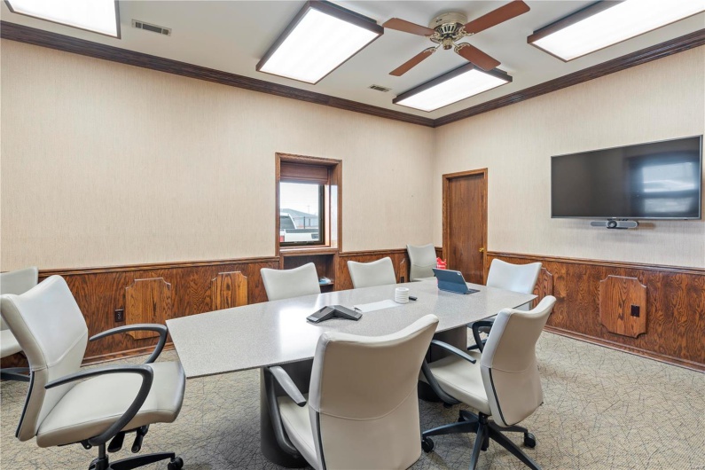 Carpeted office space with ceiling fan, ornamental molding, and wooden walls