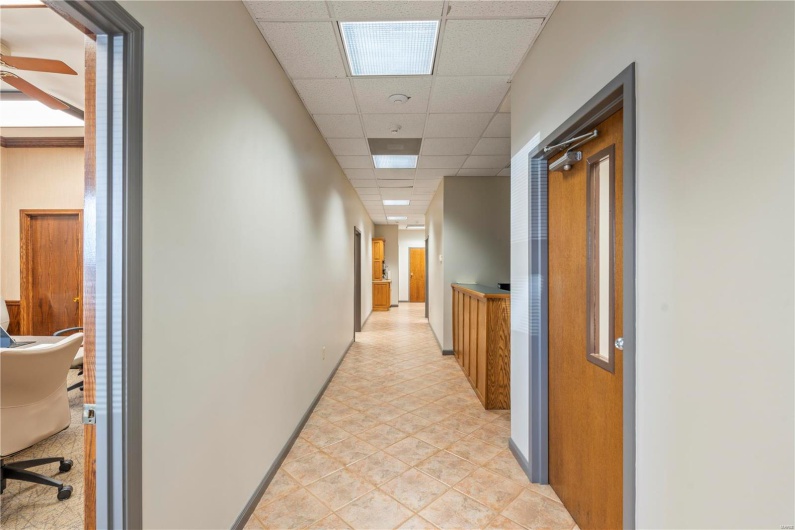 Hall with a drop ceiling and light tile patterned floors