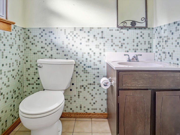 Half bathroom featuring toilet, tile walls, and tile patterned floors