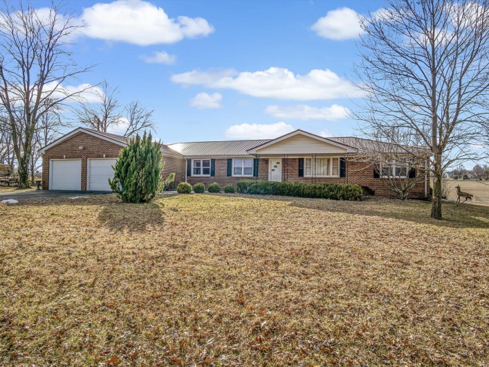 Single story home featuring an attached garage, brick siding, a front yard, and aphalt driveway