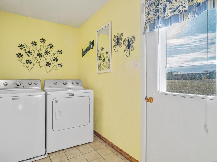 Washroom featuring washer and dryer, laundry area, light tile patterned flooring, and baseboards
