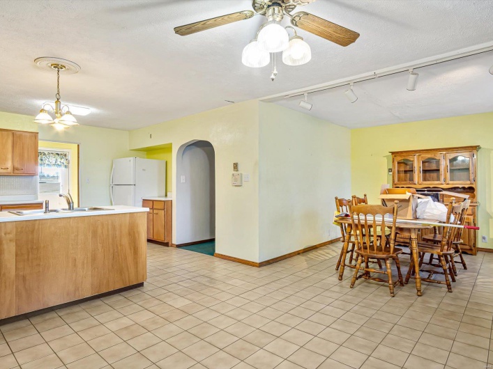 Dining space featuring baseboards, arched walkways, a textured ceiling, and ceiling fan with notable chandelier