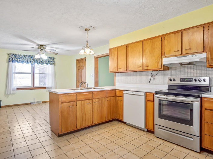 Kitchen featuring under cabinet range hood, a sink, visible vents, stainless steel electric range, and dishwasher