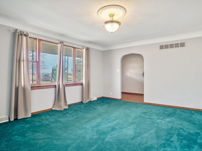 Unfurnished room with arched walkways, carpet floors, visible vents, and baseboards
