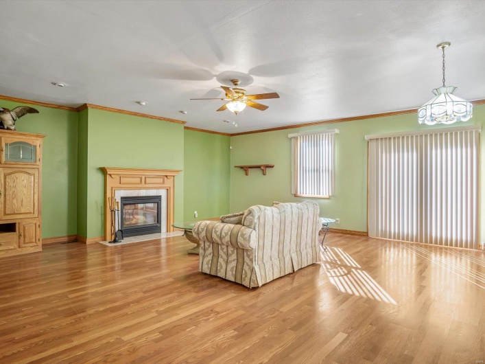 Living room featuring crown molding, light wood finished floors, a fireplace with flush hearth, and baseboards