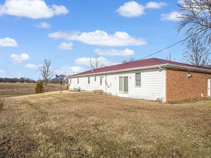 Rear view of property featuring entry steps, a yard, and brick siding