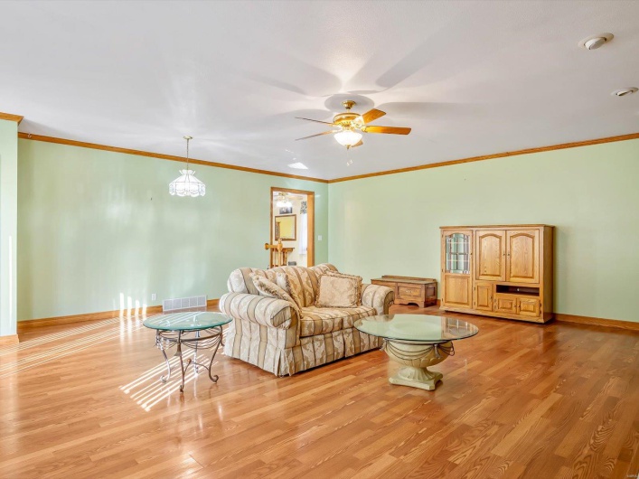 Living area featuring ornamental molding, light wood-style flooring, and baseboards