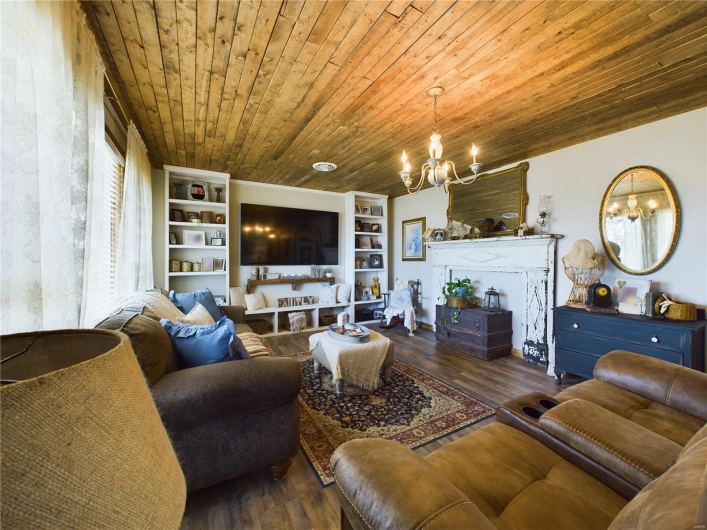 Living room with a fireplace, built in shelves, wood ceiling, an inviting chandelier, and dark hardwood / wood-style floors