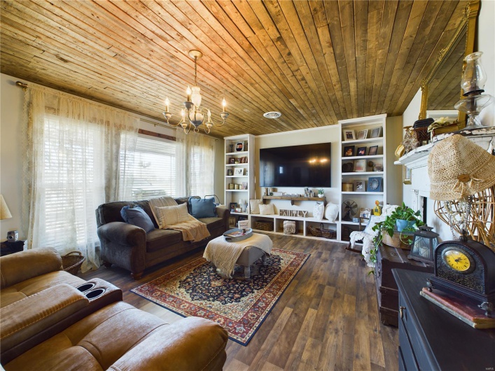 Living room with built in features, a chandelier, wooden ceiling, and dark hardwood / wood-style floors