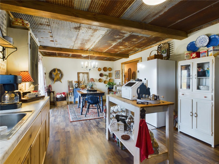 Kitchen with beamed ceiling, dark wood-type flooring, pendant lighting, and a chandelier