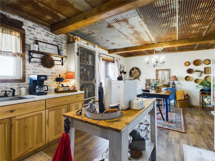 Kitchen featuring beam ceiling, dark wood-type flooring, pendant lighting, wooden ceiling, and sink