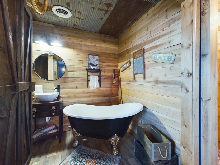 Bathroom with wood ceiling, a tub to relax in, wood-type flooring, vanity, and wooden walls