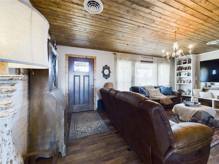 Living room featuring dark wood-type flooring, built in shelves, wood ceiling, and a notable chandelier