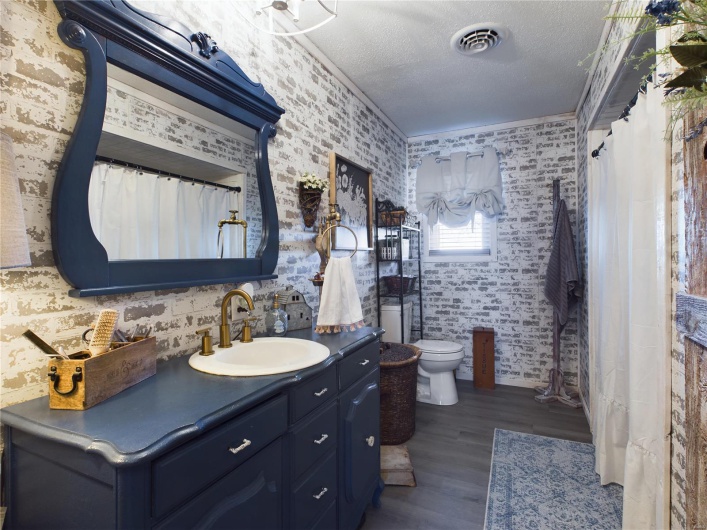 Bathroom featuring hardwood / wood-style floors, vanity, a textured ceiling, toilet, and ornamental molding