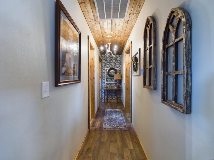 Hall with wood ceiling, dark hardwood / wood-style floors, and an inviting chandelier