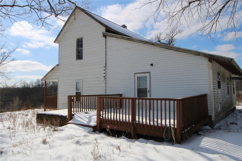 Snow covered back of property featuring a chimney and a deck
