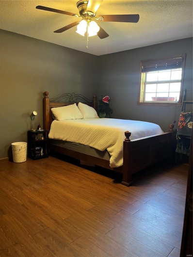 Bedroom featuring ceiling fan, a textured ceiling, and wood finished floors