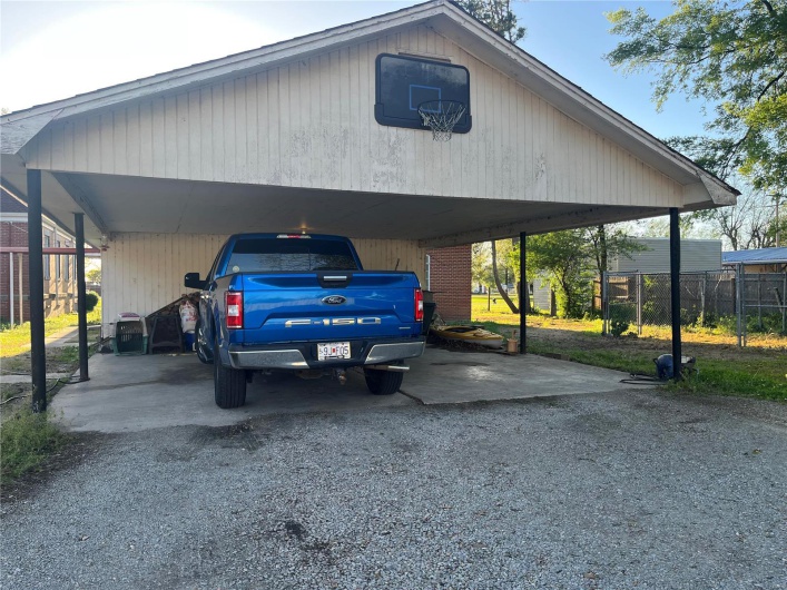 View of parking with driveway and fence