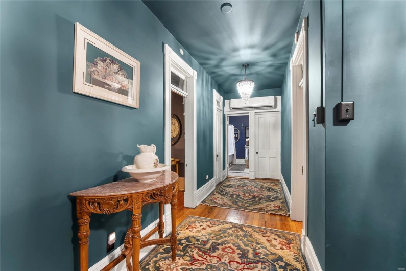 Corridor featuring hardwood floors, a notable chandelier, and a wall mounted AC
