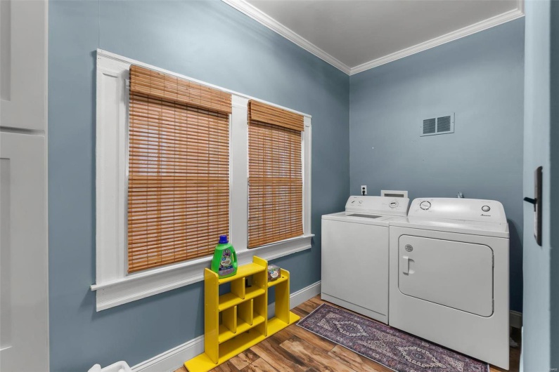 Clothes washing area with wood look tile floors, ornamental molding, and washer and dryer