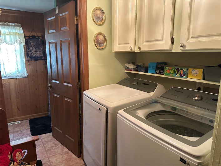 Washroom with visible vents, cabinet space, wooden walls, and separate washer and dryer