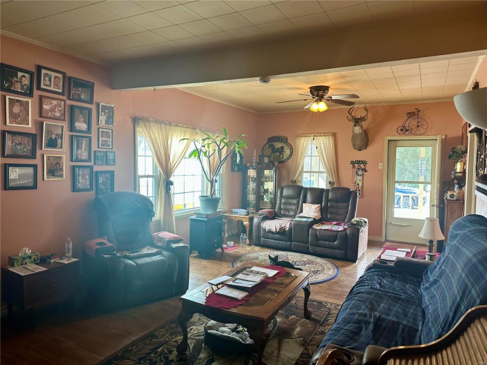 Living room featuring ceiling fan, ornamental molding, beam ceiling, and baseboards