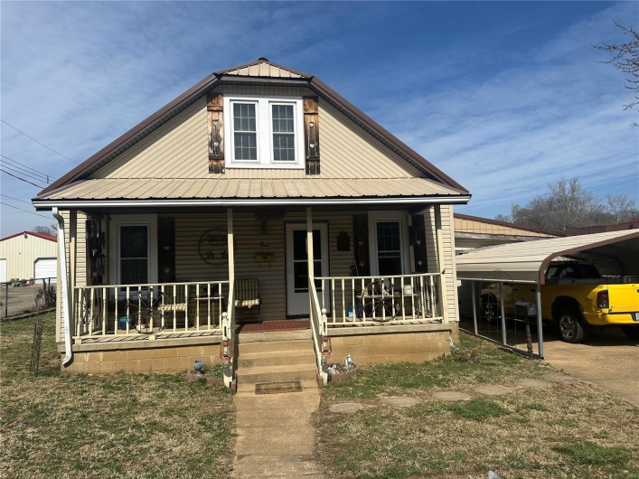 View of front of house featuring a detached carport, covered porch, and metal roof