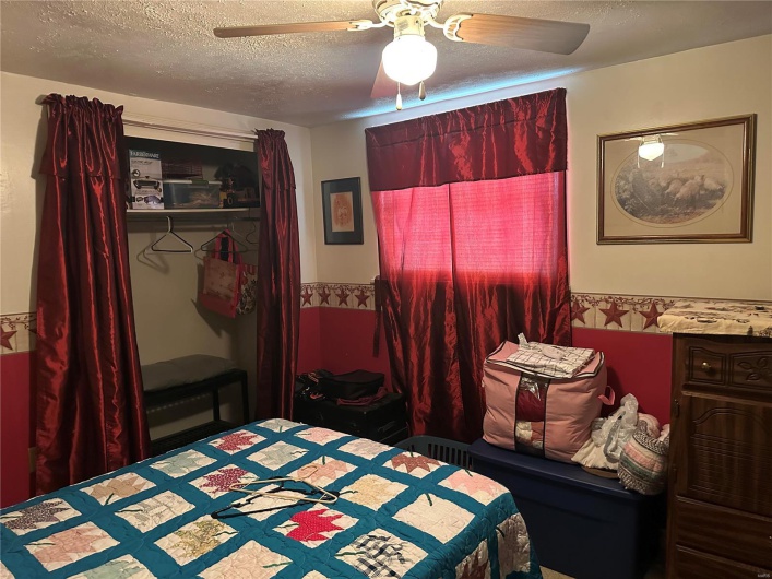 Bedroom with a textured ceiling, a closet, and a ceiling fan