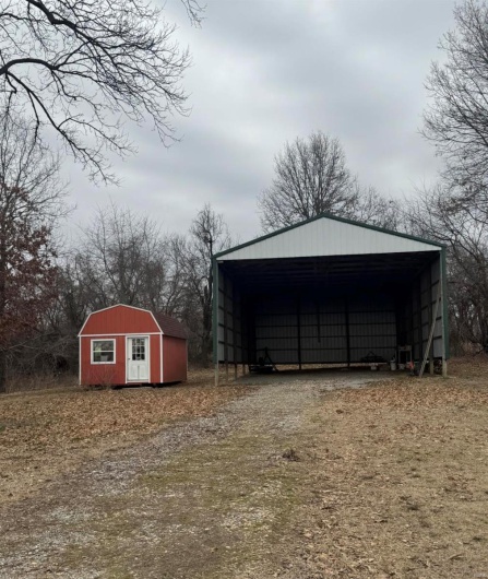 View of outbuilding featuring an outbuilding, a carport, and dirt driveway