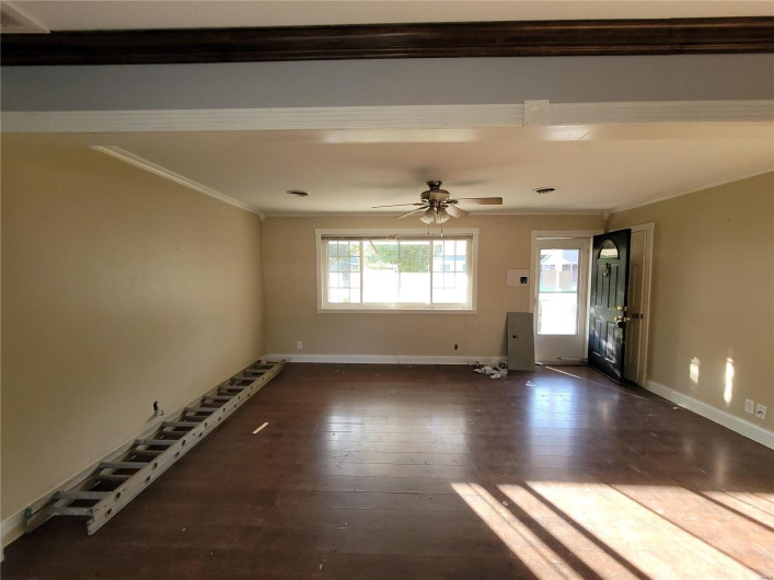 Unfurnished room with baseboards, dark wood-type flooring, a ceiling fan, and crown molding