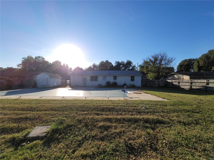 View of front of property with an outdoor structure, fence, a front lawn, and a storage shed
