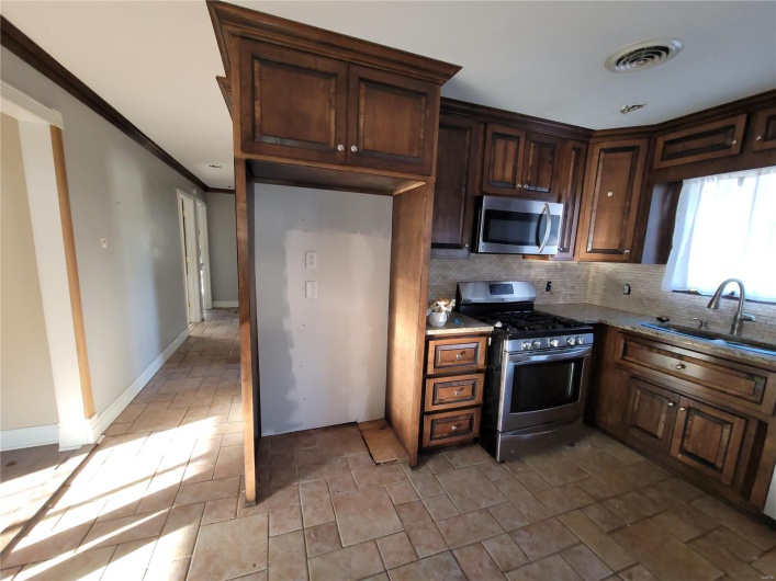 Kitchen featuring tasteful backsplash, visible vents, appliances with stainless steel finishes, light stone counters, and a sink