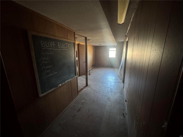 Hallway featuring wood walls and a textured ceiling