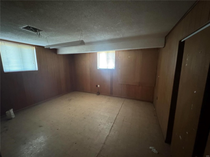 Basement with a textured ceiling and wood walls