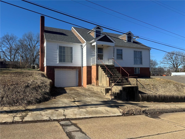 View of front of property featuring concrete driveway, a shingled roof, and an attached garage