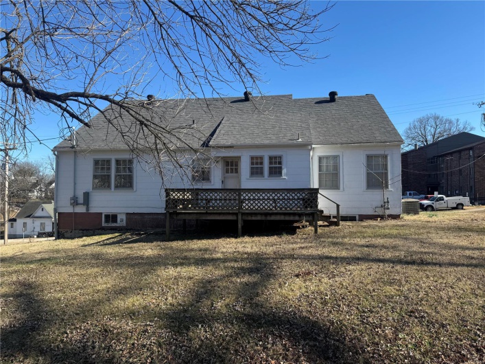 Back of house featuring roof with shingles, a yard, and a wooden deck