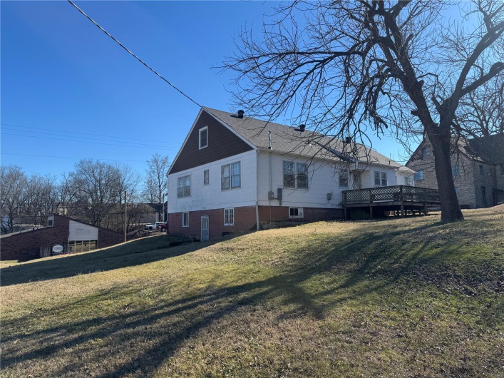 View of side of property featuring a deck and a lawn