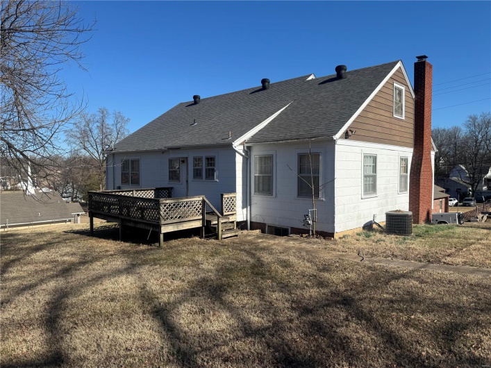 Rear view of house with central AC unit, a lawn, a chimney, roof with shingles, and a deck